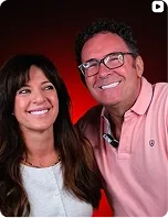 A couple smiling together, on red