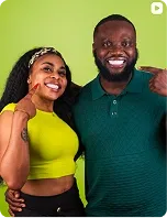 A woman and a man smiling together, on green