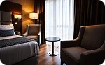 The foot of a bed, an armchair and a round side table by the window